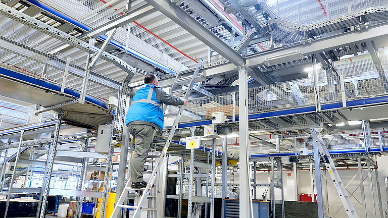 Um Störungen in der Fördertechnik zu beseitigen, müssen Mitarbeitende auf Leitern steigen. Hier steht Schichtleiter Christian Appel auf der Leiter.
