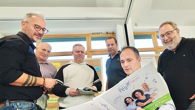 Fünf Seminarteilnehmer lassen sich vom Dozenten das PegA-Programm erläutern.