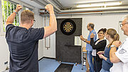 Kolleginnen und Kollegen der Regionaldirektion in Bonn spielen eine Runde Darts in der Pause