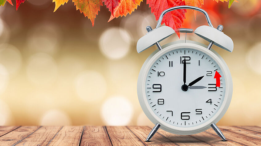 Auf einem Wecker ist mit einem Pfeil markiert, dass die Uhr von 3 Uhr auf 2 Uhr zurückgestellt werden muss. 