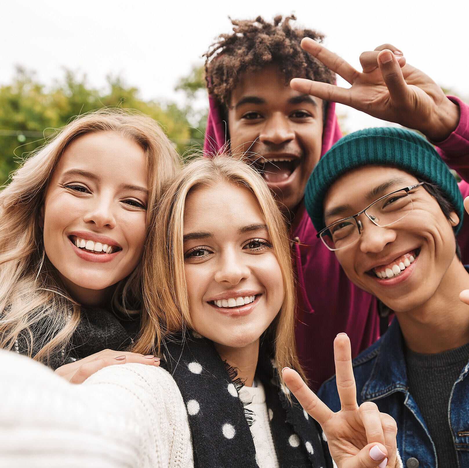 Vier Jugendliche nehmen ein Selfie auf und zeigen das Peace-Zeichen mit ihren Händen
