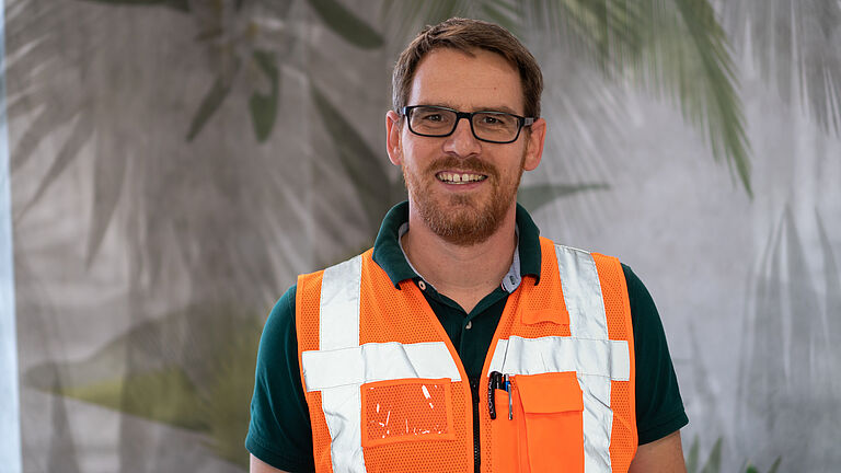 Porträt von Senior Logistik Manager Markus Moch in orangefarbener Warnweste. 