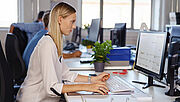 Eine Frau sitzt am PC und recherchiert Informationen
