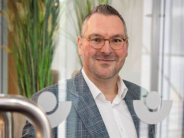 Der Geschäftsführer Herr Schäffner steht an einer Glastür.