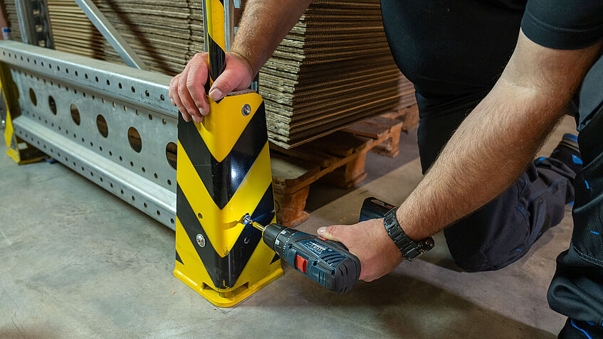 Mitarbeiter schraubt die Signalstange an den Eckenschutz.