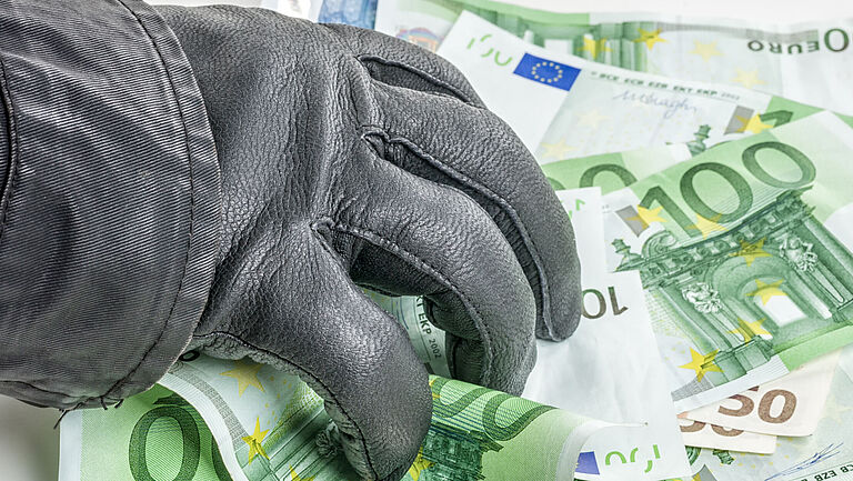 Hand mit schwarzem Lederhandschuh entwendet Euro-Geldscheine