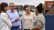 Auf der Dachterrasse der Regionaldirektion in München unterhalten sich vier Mitarbeitende