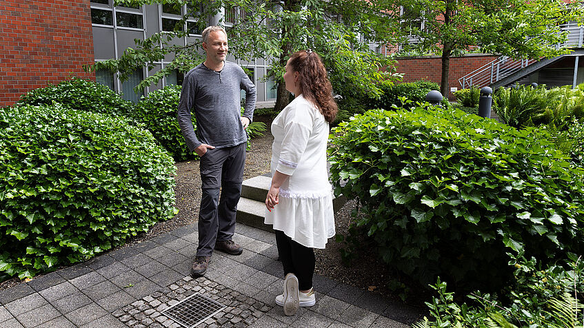 Zwei Kollegen unterhalten sich im begrünten Innenhof der Regionaldirektion in Essen