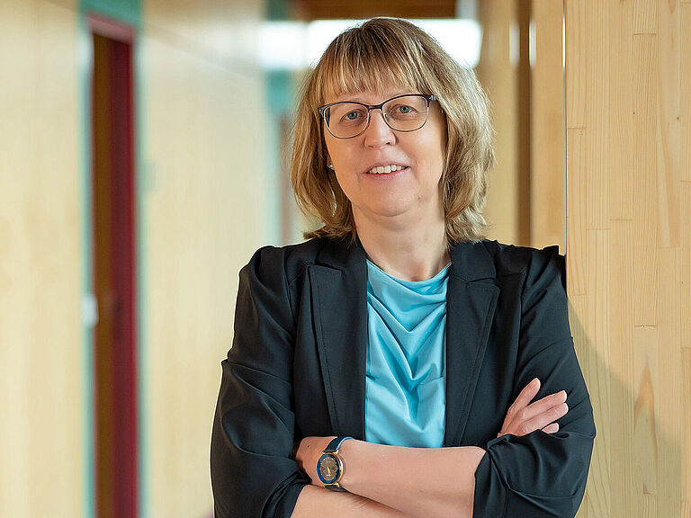 Bettina Wenig steht und hält die Arme verschränkt.