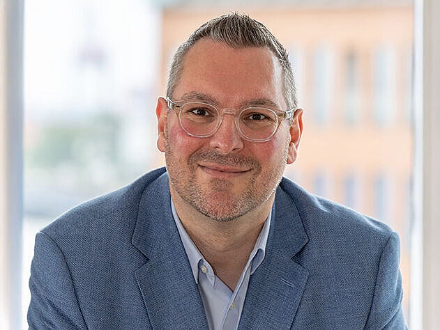 Herr Schäffner RD Hamburg Porträt Der Geschäftsführer Herr Schäffner sitzt an einem Schreibtisch und schaut freundlich in die Kamera.