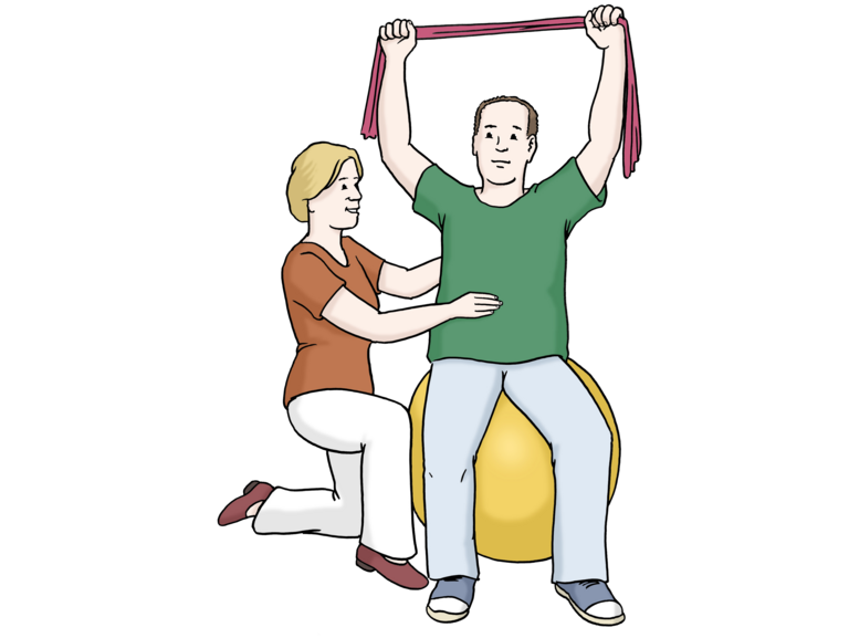 Eine Physiotherapeutin unterstützt im Knien einen Mann an der Hüfte, der auf einem Hüpfball sitzt und in seinen gehobenen armen einen Schal über seinen Kopf hält.