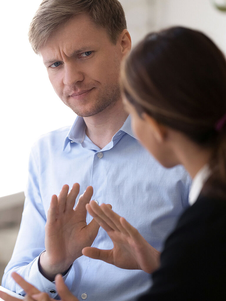 Ein Mann schaut skeptisch auf eine Frau neben ihn, die auf ihn einredet