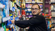 Porträt Rewe-Azubi Achilleas Tsandekidis vor Warenregalen