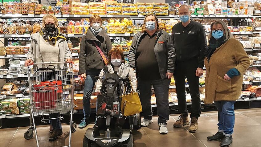 Das Bild zeigt die Arbeitsgruppe vom Inklusionsbeirat sowie die Kaufleute Markus Hetzenegger (Edeka) und Ursula Wintgens (Rewe) im abgedunkelten Supermarkt