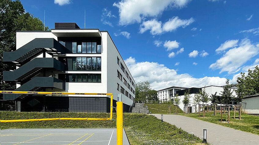 Wohnhaus für Studierende, davor ein Sportplatz mit Volleyballfeld