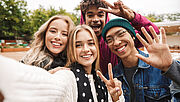 Vier Jugendliche nehmen ein Selfie auf und zeigen das Peace-Zeichen mit ihren Händen
