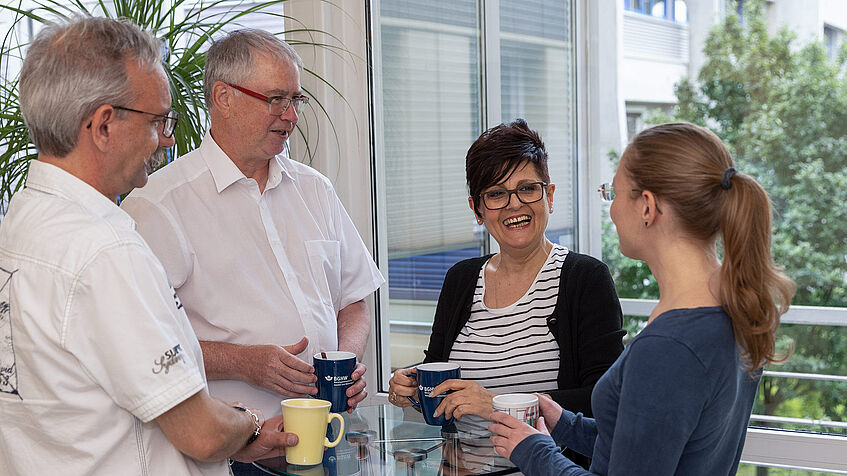 Vier Kolleginnen und Kollegen der Regionaldirektion in Bonn unterhalten sich in ihrer Kaffeepause