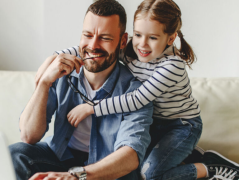 Ein Vater sitzt mit seiner Tochter im Home Office