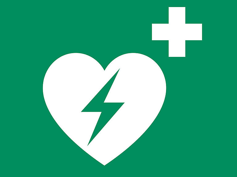 Rettungszeichen Defibrillator: Ein Herz mit Blitz, darüber ein weißes Kreuz auf grünem Hintergrund