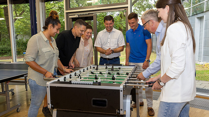 Am Tischkicker der Regionaldirektion in München spielen Kolleginnen und Kollegen eine Partie gegeneinander