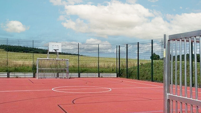 Leerer Sportplatz mit Fußballtor und Basketballkorb 