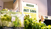 Damit weniger weggeschmissen wird: Ein Schild „Verpackung mit Sinn” weist darauf hin, warum die Bio Company bestimmte Obst- und Gemüsesorten doch verpackt. 