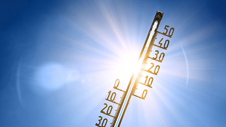 Ein Thermometer ragt in den sonnigen Himmel. Es zeigt 34 Grad Celsius an.