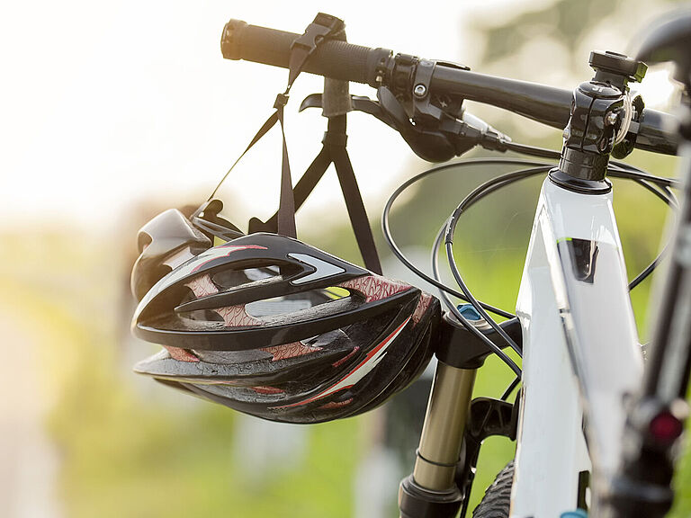 Ein Helm hängt im Sonnenschein am Fahrradlenker