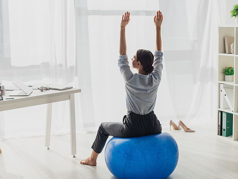 Eine Frau sitzt auf einem Ball in ihrem Büro