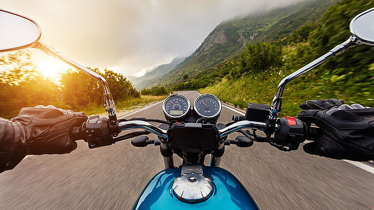 Ein Motorradfahrer fährt im Frühjahr auf der Straße